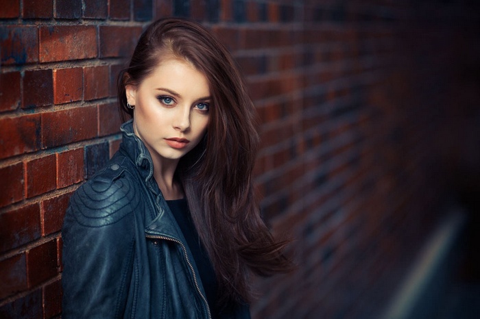 Portrait of Isabel leaning against a brick wall