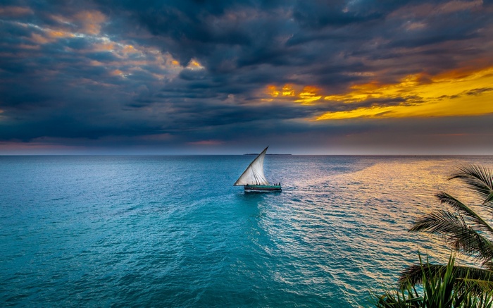 Sailboat on the ocean at sunset with dramatic clouds