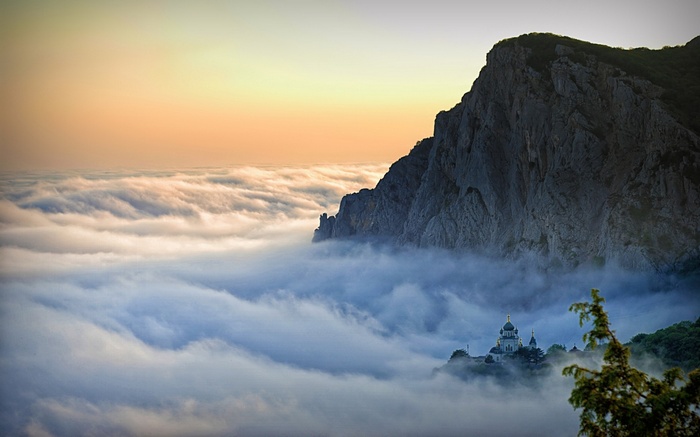 Church on a cliff above clouds in Crimea at sunset