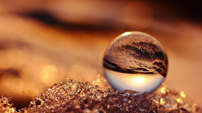 Glass sphere reflecting sunlight on ice