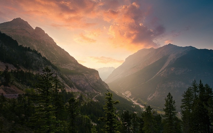 Valley and mountains at sunset with clouds and trees