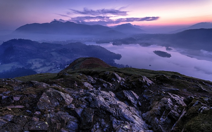 Misty mountains and lake at sunrise in England
