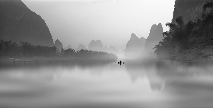 Fisherman on a boat in a misty river landscape in China