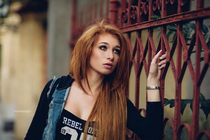 Woman with red hair leaning on a red fence