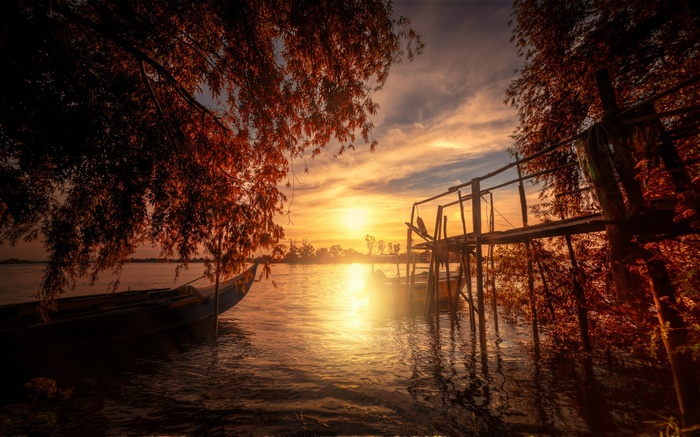 Sunset over a lake with a boat and a dock
