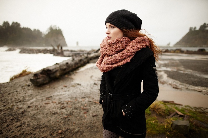 Redhead woman in black coat and scarf on beach