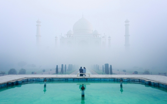 Couple on bench overlooking Taj Mahal in mist