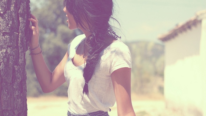 Woman with braided hair leaning on a tree