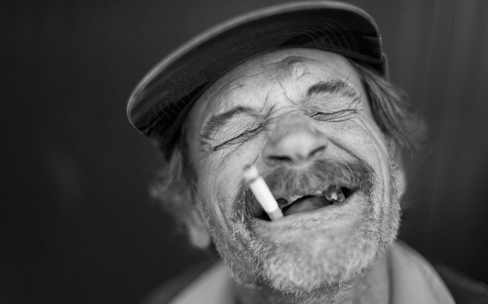 Man wearing a cap smoking and laughing