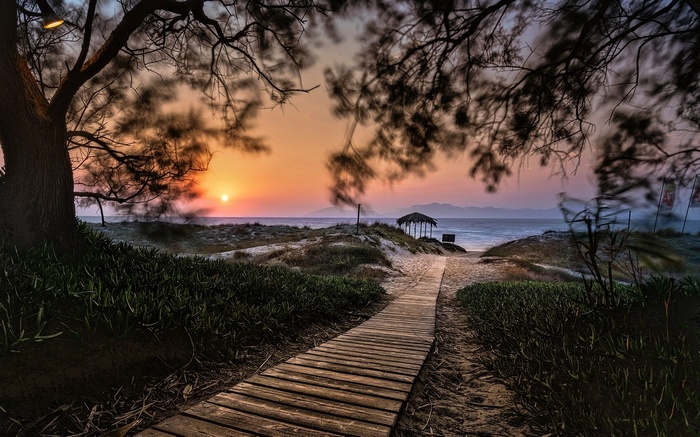 Wooden walkway to a beach hut at sunset in Greece