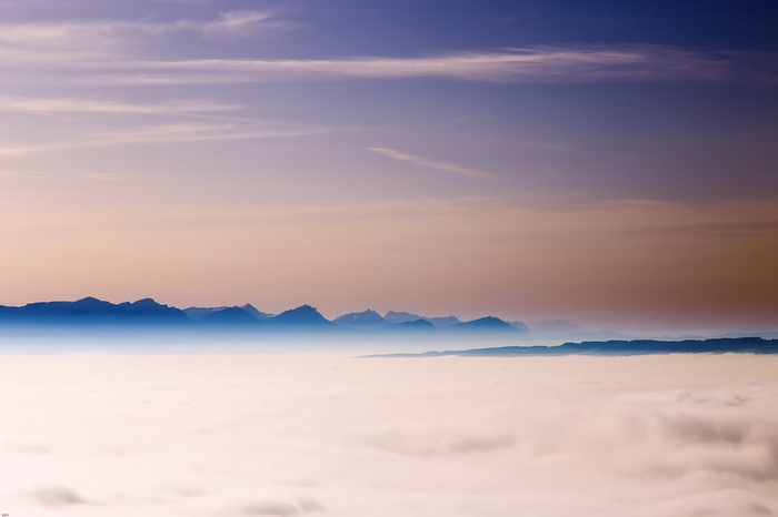 Mountain range above clouds at sunset
