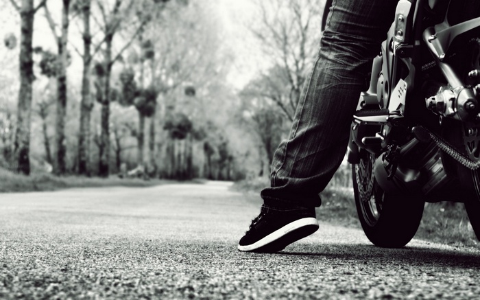 Monochrome shot of a person on a motorcycle on a road