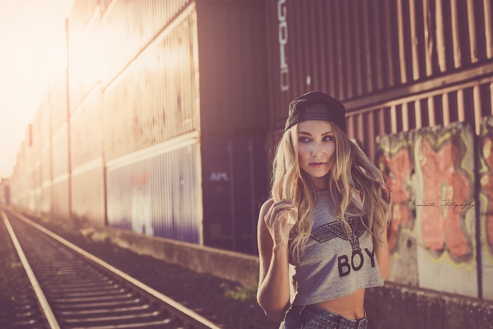 Woman with baseball cap and crop top by train tracks