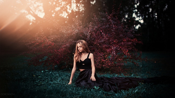 Woman in black dress sitting in grass