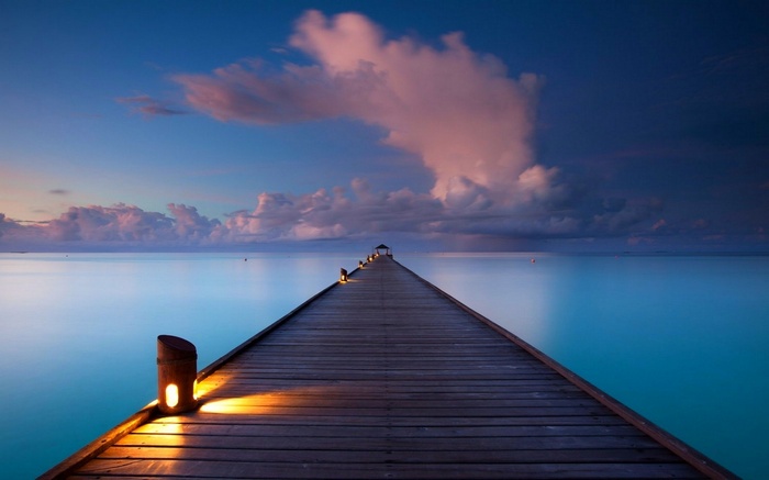 Wooden pier extending into the ocean at sunset