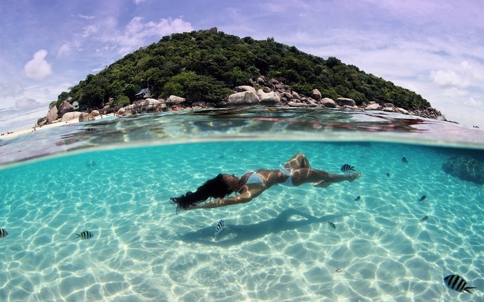 Woman swimming underwater near tropical island in Thailand