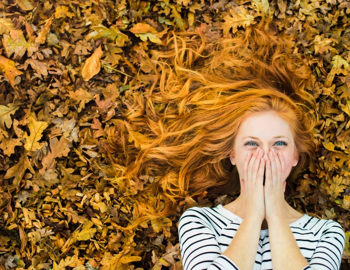 Redhead woman lying on autumn leaves