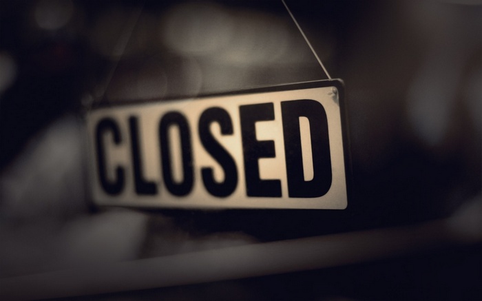 A sign that says CLOSED hanging in a window