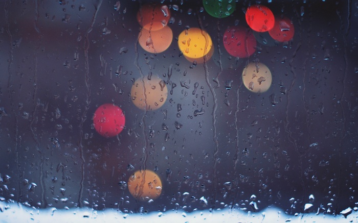 Raindrops on glass with blurred colorful lights