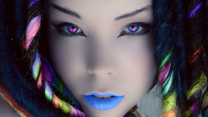 Close-up of a woman with colorful dreadlocks and vibrant eyes