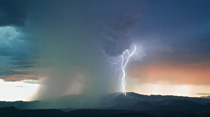 Lightning strikes a mountain during a storm with rain