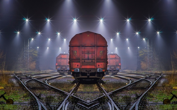 Nighttime train yard with red cargo trains and bright lights