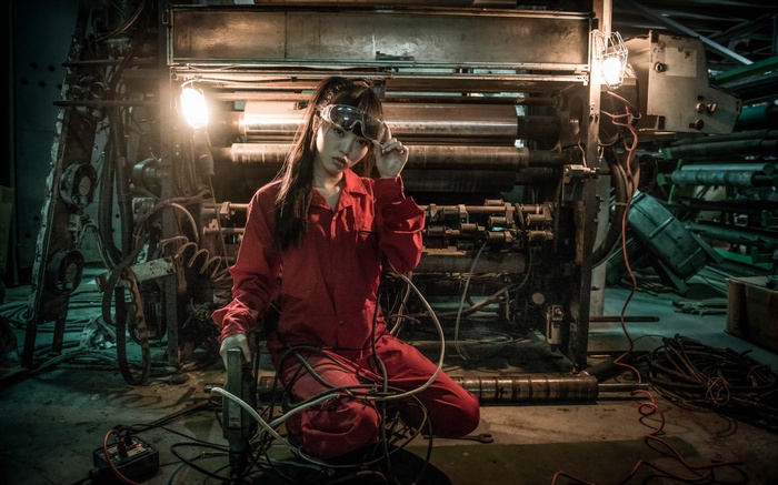 Asian model in red jumpsuit with goggles near machinery