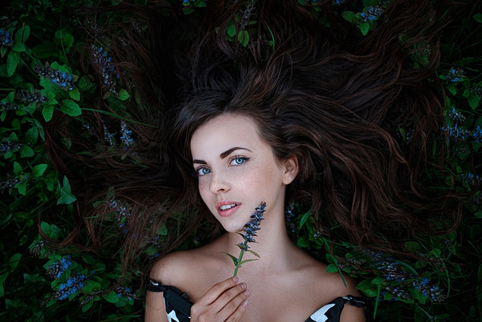 Woman with blue eyes lying in flowers