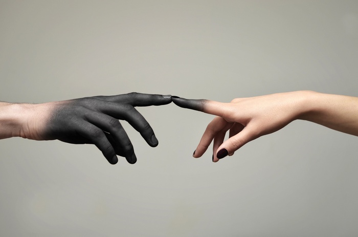 Two hands touching fingers, one black, one white