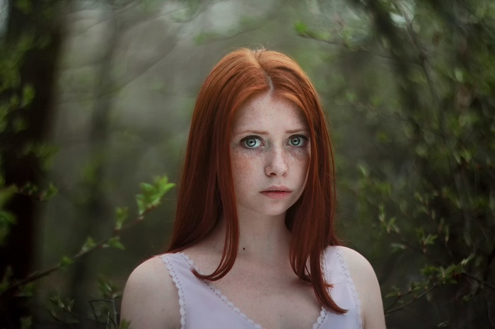 Redhead woman with freckles in a forest