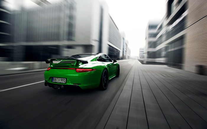 Green Porsche 911 Carrera 4S driving on a city street