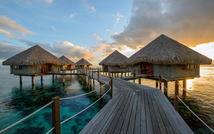Overwater bungalows on a tropical resort at sunset