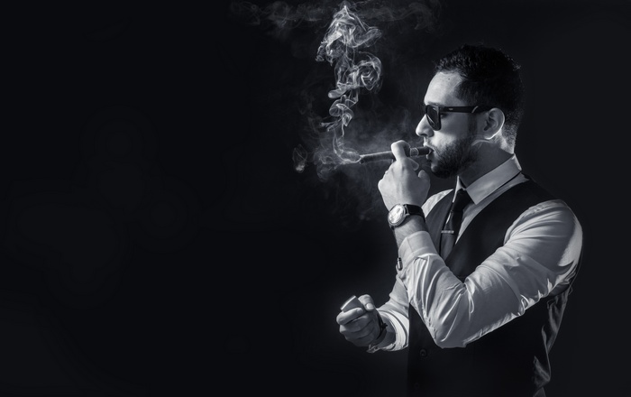 Man in suit smoking a cigar with smoke