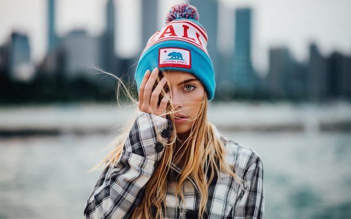 Woman in California beanie in front of cityscape