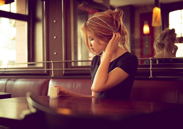 Camille, a model, sits in a cafe with a cup