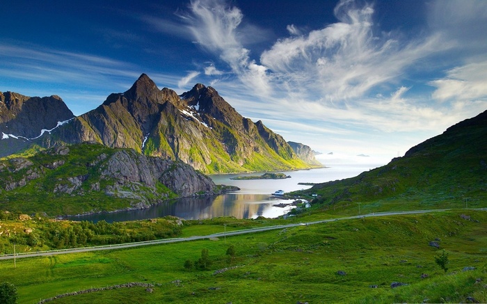 Green mountains and a lake under a blue sky