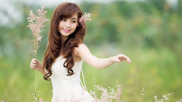 Asian woman in white dress holding flowers in nature