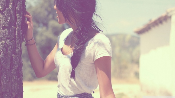 Woman with braid leaning on a tree