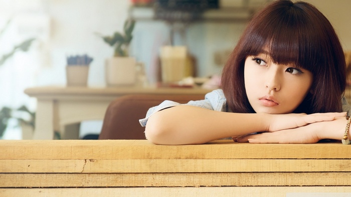 Asian woman with brown hair resting her head on her arms