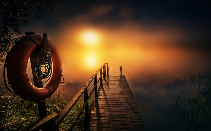 Wooden dock on a misty lake at sunset