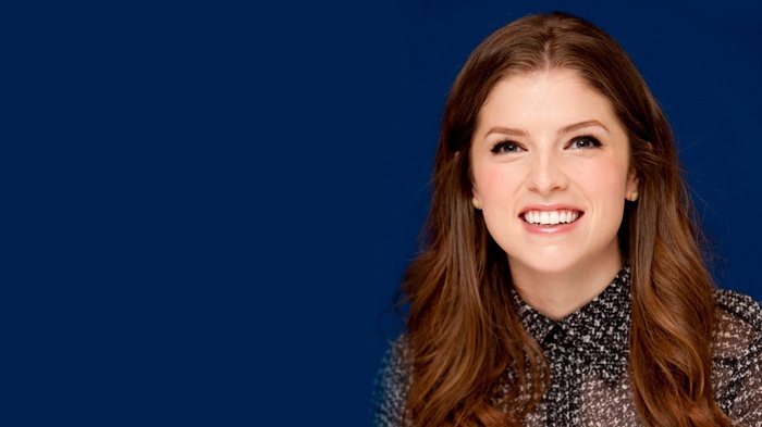 Anna Kendrick smiling against a blue background