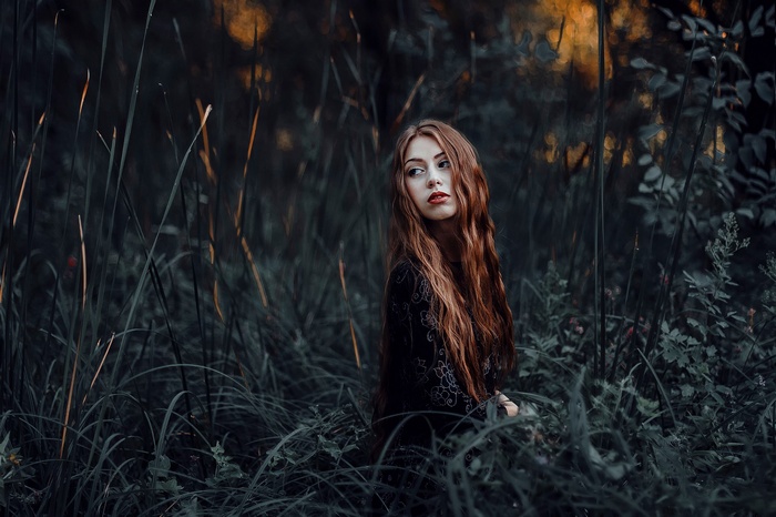 Redhead woman with long hair in tall grass