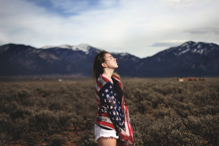 Woman wrapped in American flag in front of mountains
