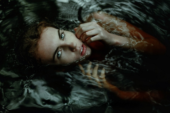 Woman with blue eyes submerged in dark water