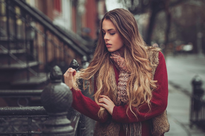 Woman with blonde hair wearing a sweater and scarf