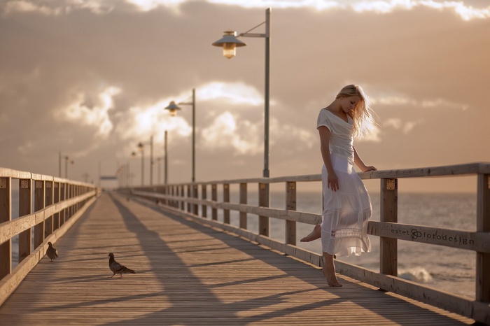 Woman in white dress on a pier with seagulls