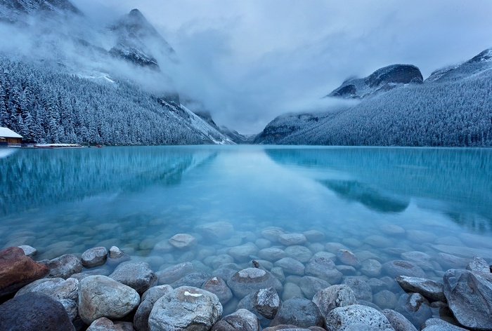 Turquoise lake with snow-covered mountains and forest