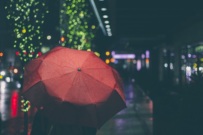 Person holding a red umbrella at night