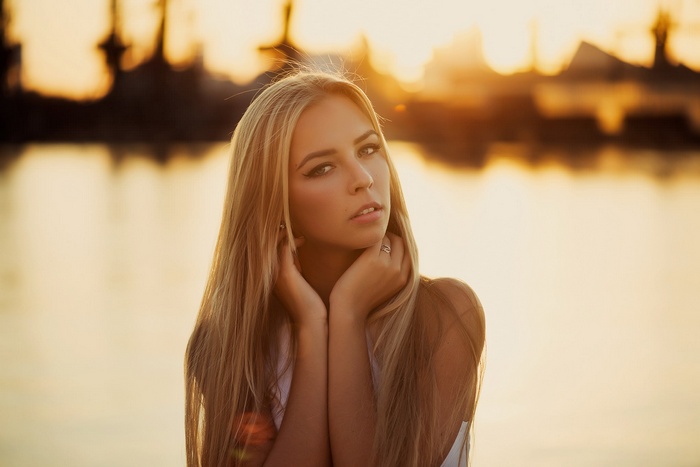 Blonde woman posing by the water at sunset