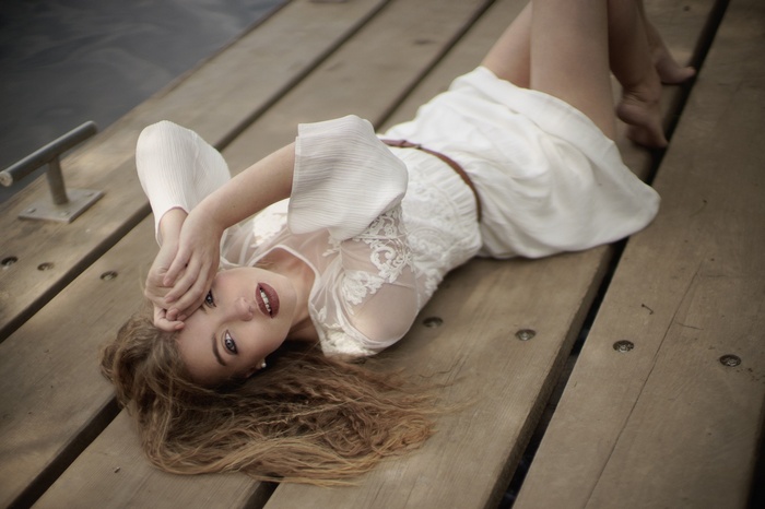 Woman in white dress lying on a wooden pier